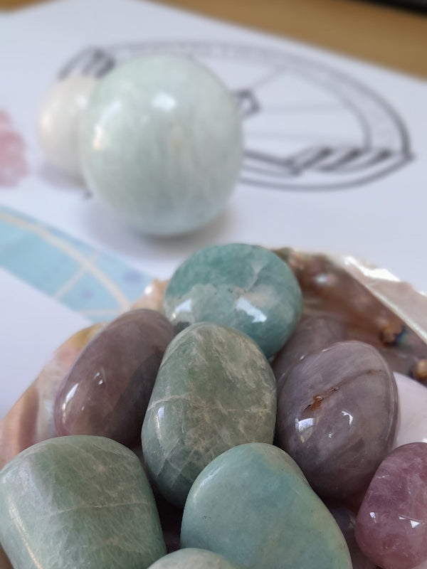 abalone shell full of crystals with a green moonstone sphere in the background