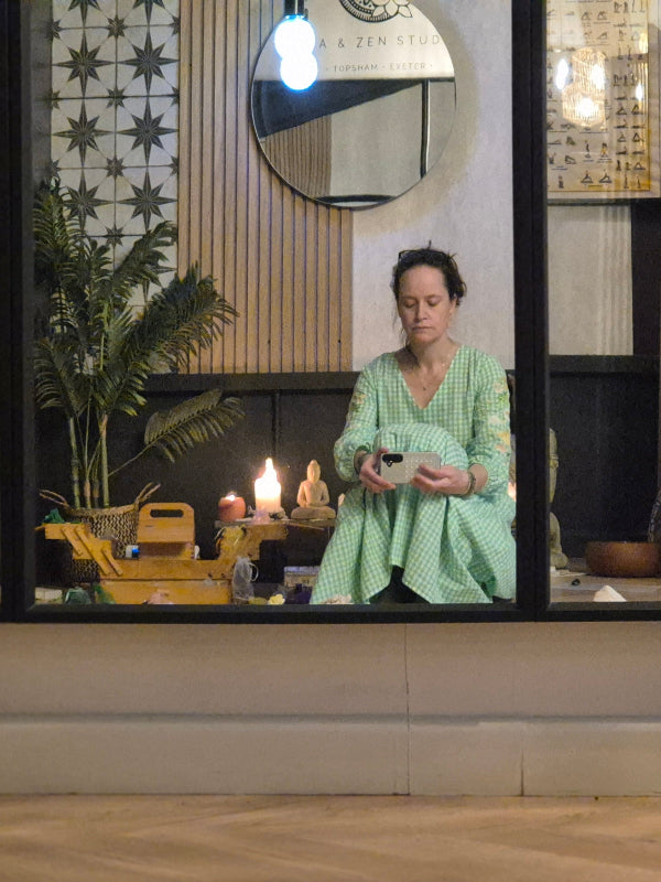 woman crouched on the studio floor in front of a mirror during a crystal circle