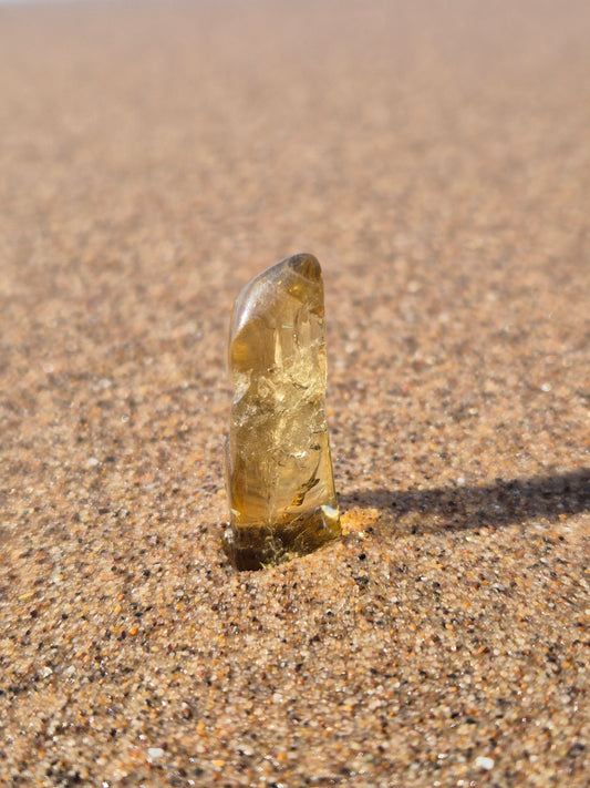 a golden citrine standing on sand