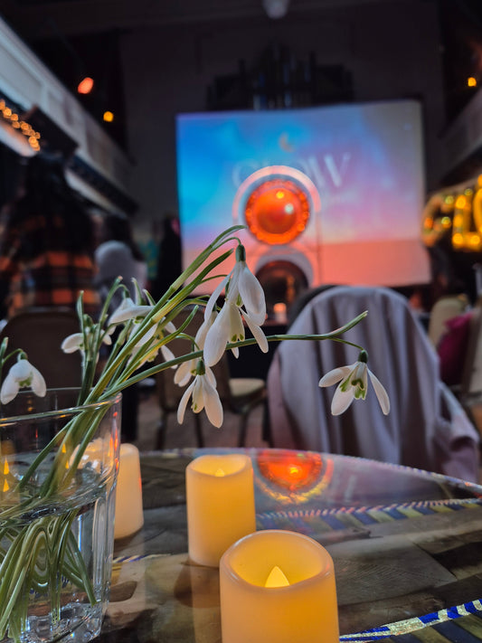 Image of a table set with candles and a vase of delicate snowdrops 
