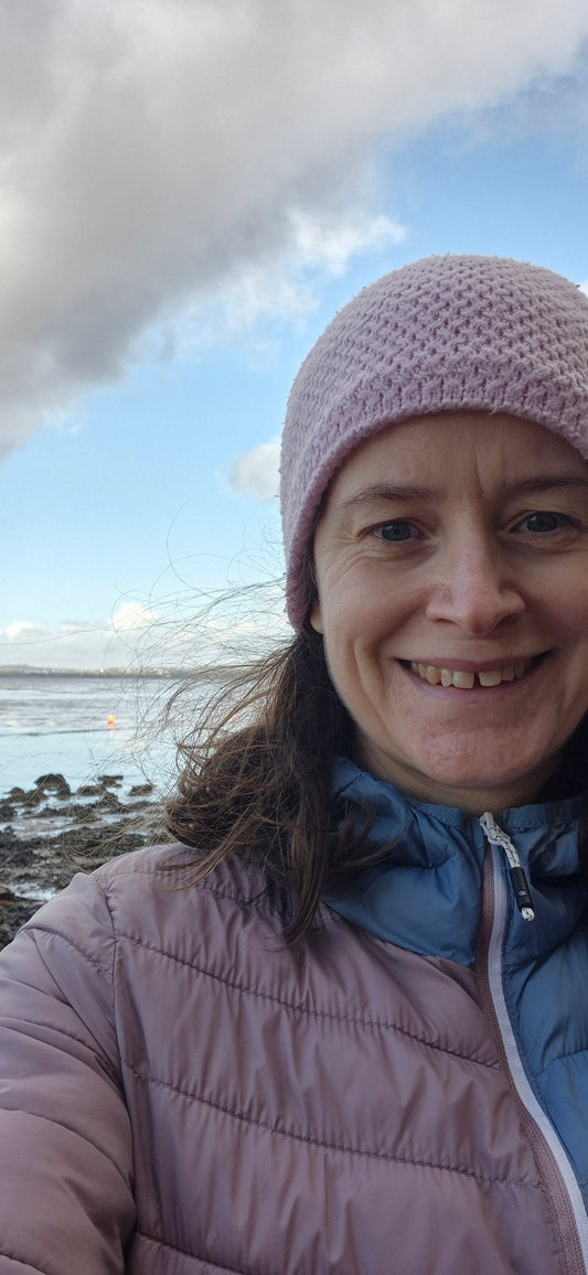 Image of Vicky with the Exe estuary over her shoulder. She's wearing a pink hat and a lilac and blue coat 