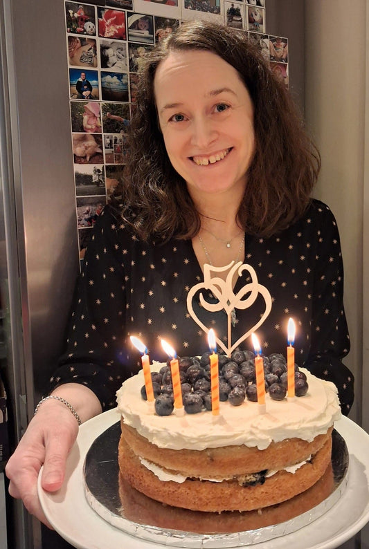 Image of a woman (me Vicky) holding a 50th birthday cake